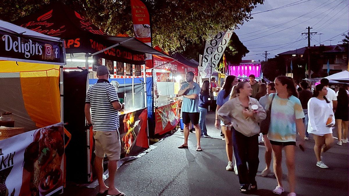People walking through a night market with food stalls
