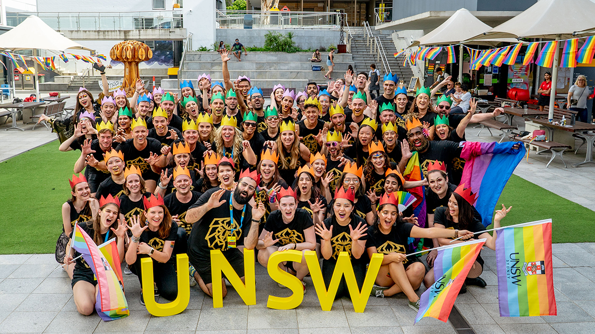 A group of UNSW students and staff in colourful party hats with rainbow flags