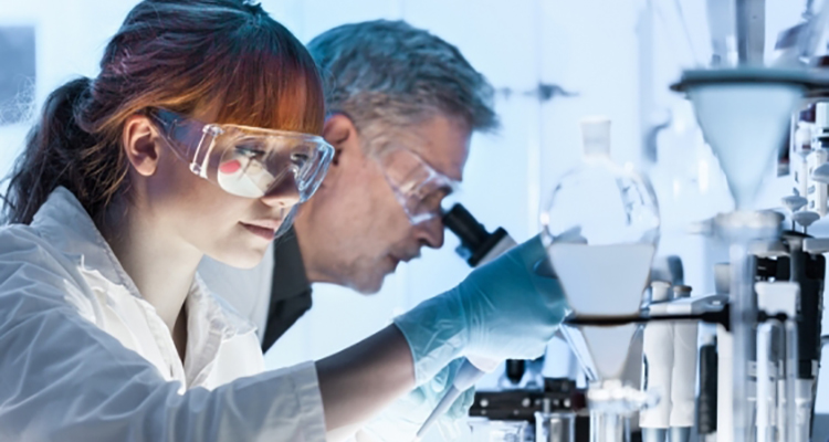 scientists peering into microscope