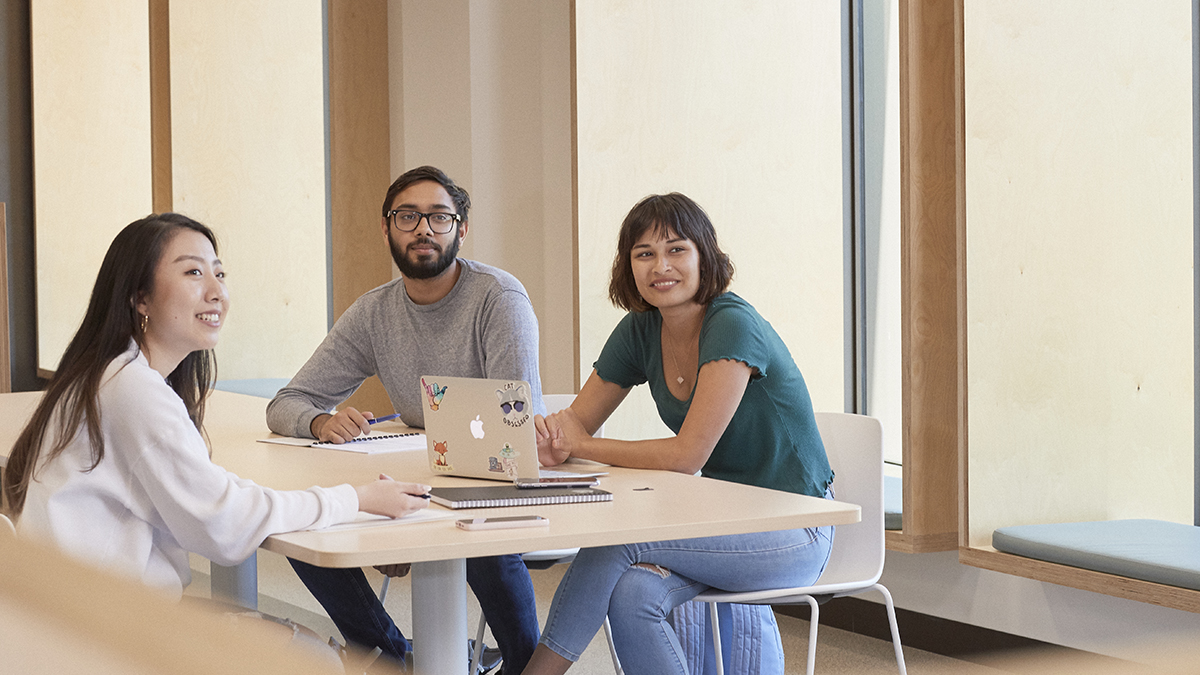 Three people sitting at a table looking to the right