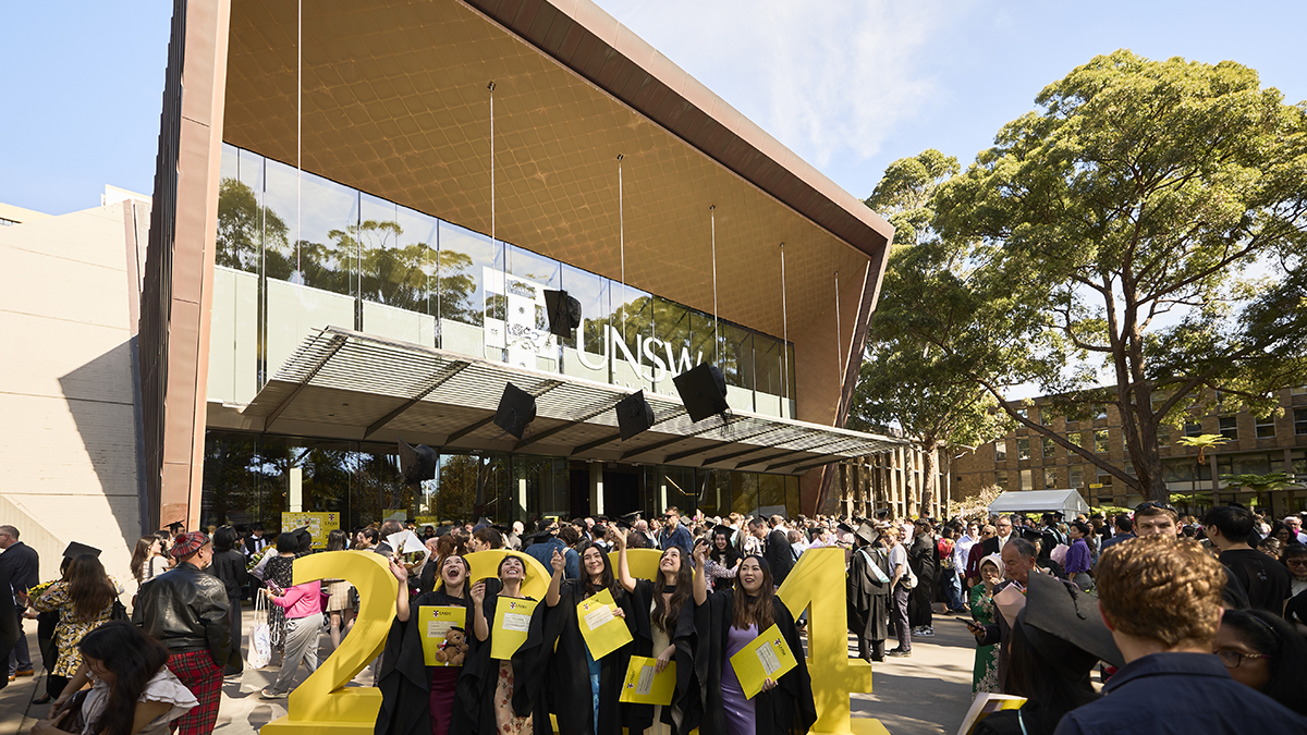 Graduates in gowns outside the Clancy Auditorium, throwing their mortarboards in the air