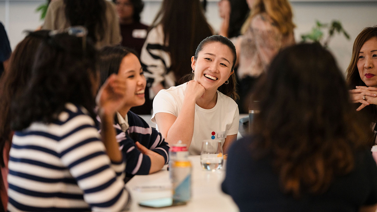 A group of women gathered at a table smiling and talking