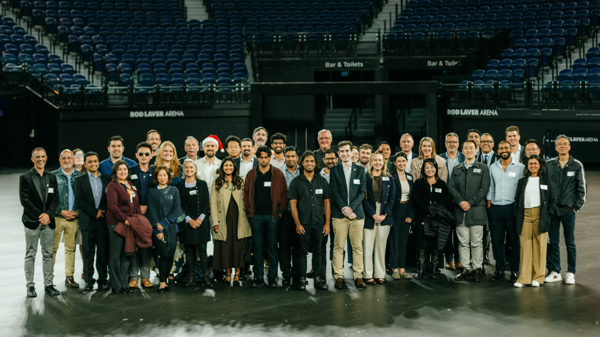 A group shot of many alumni in an arena.