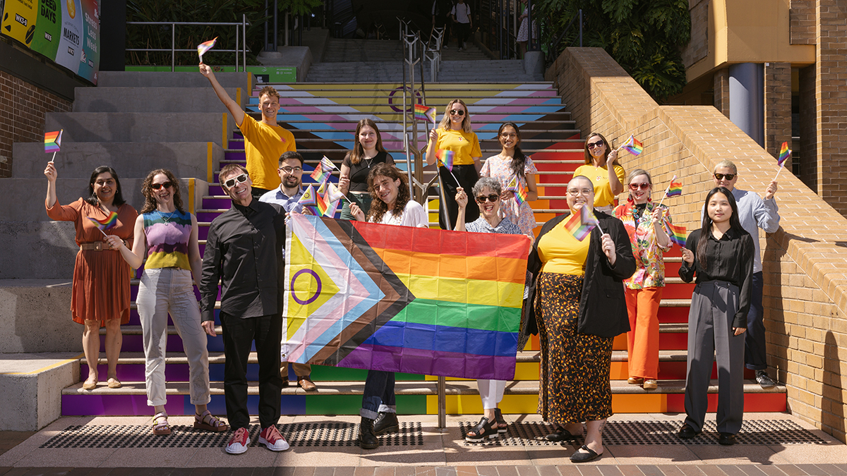 UNSW staff gathered at the Basser Steps with rainbow flags