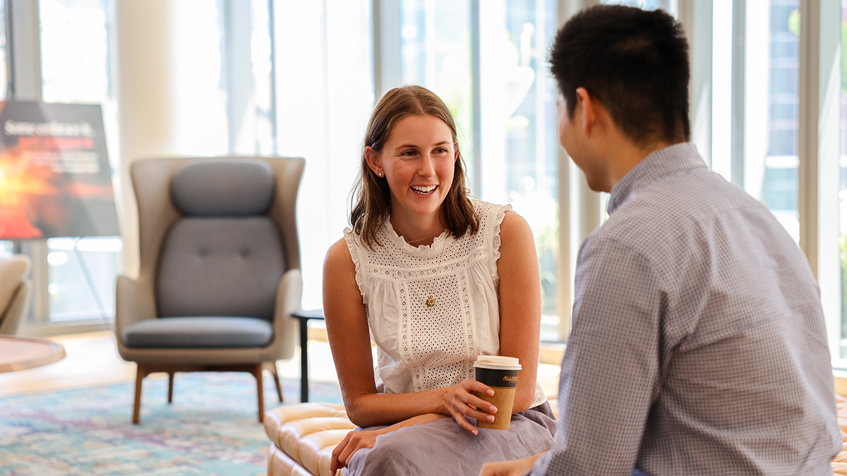 A seated woman smiling and talking to a man 