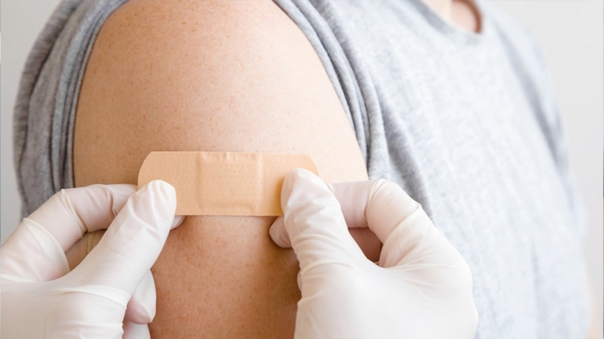 Someone getting a plaster on their arm, following a vaccine