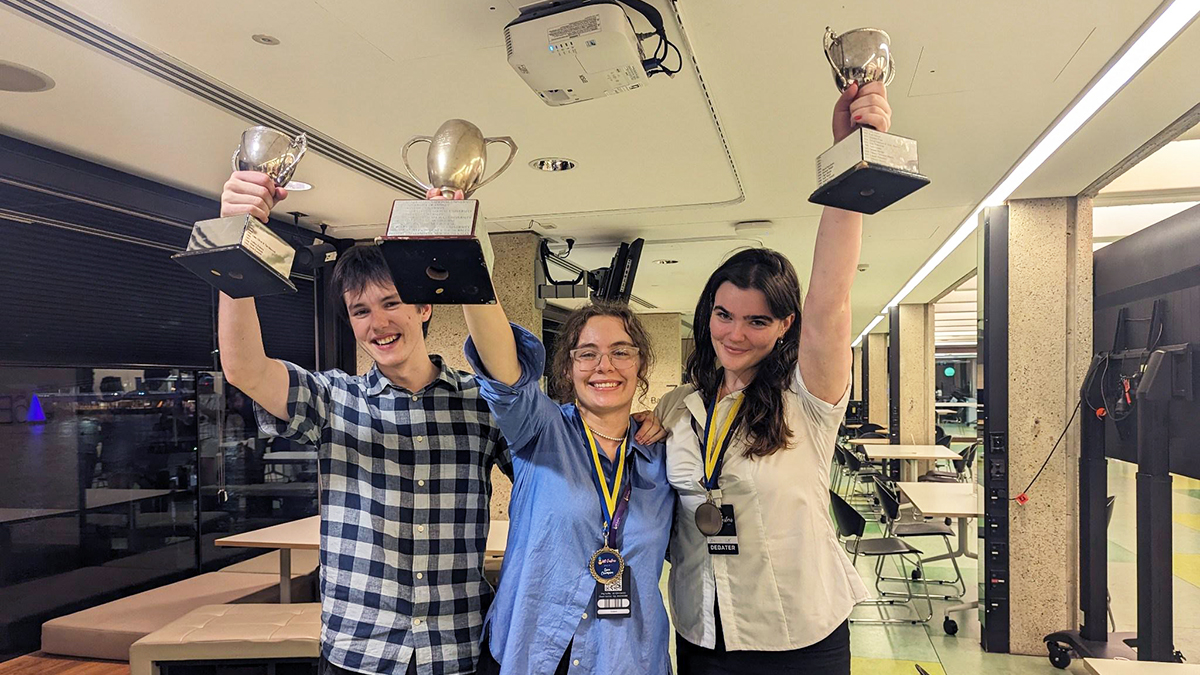 Lachie Doyle holding his Novice Best Speaker trophy, Liv Bishara holding the Australian Intervarsity Debating Championship trophy and Conna Leslie-Keefe holding her Overall Best Speaker trophy