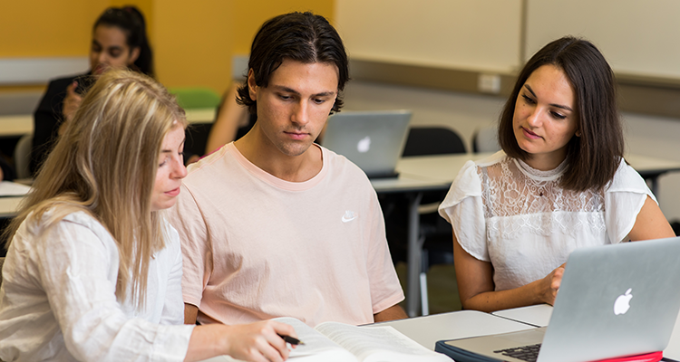 Three students in discussion in the classroom