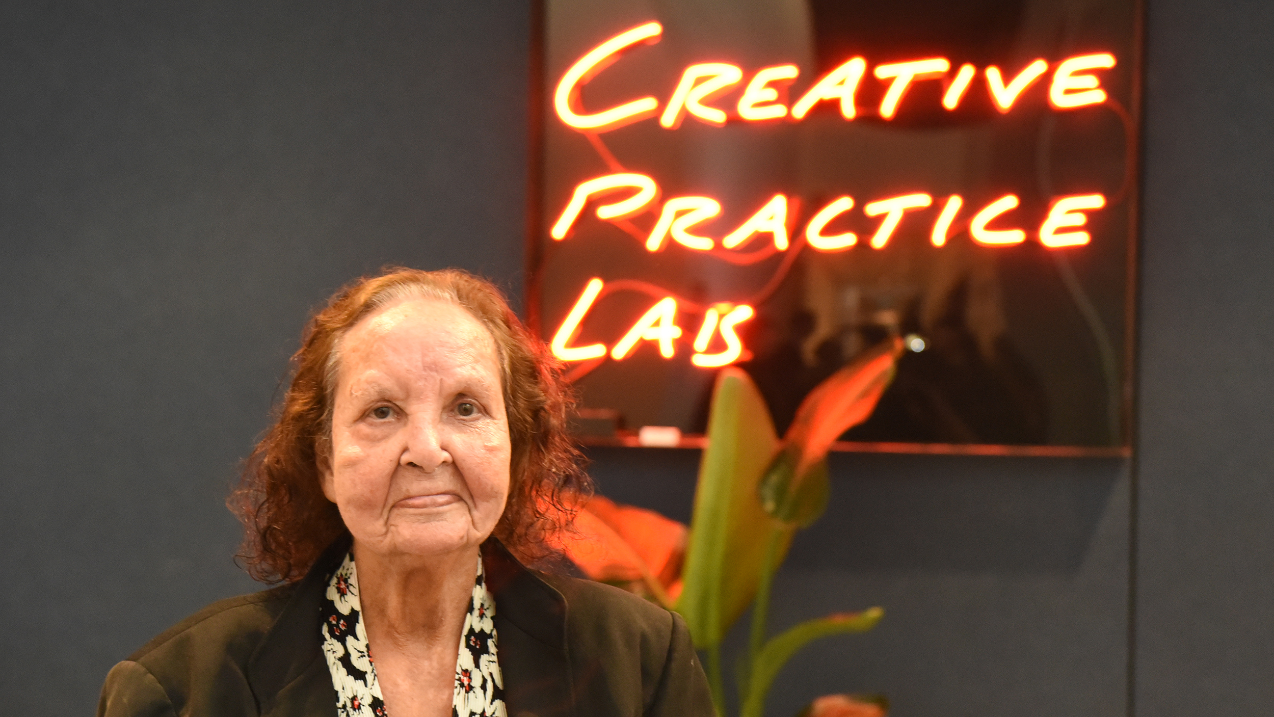 Artist Esme Timbery in front of neon sign