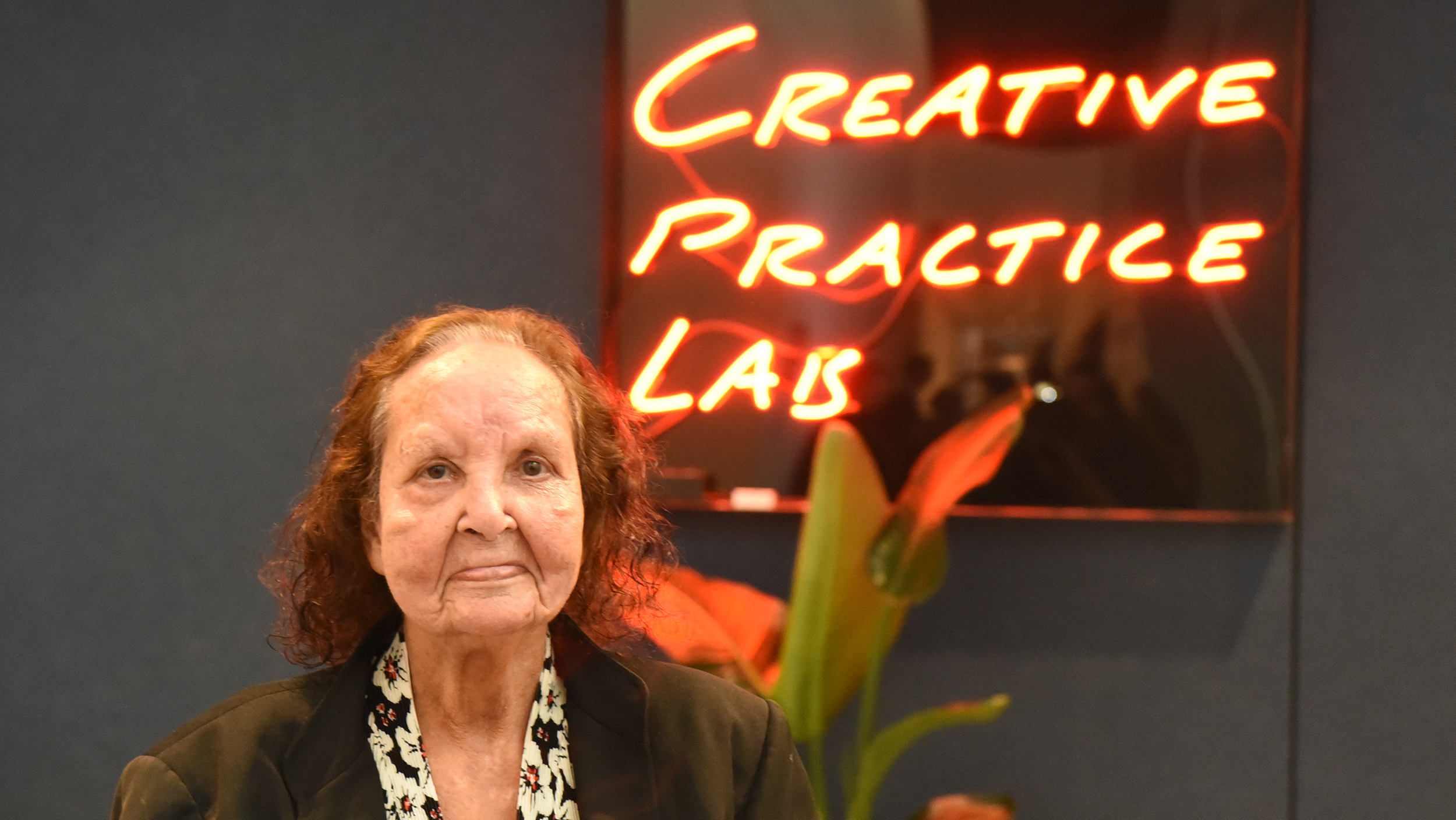 Artist Esme Timbery in front of neon sign 