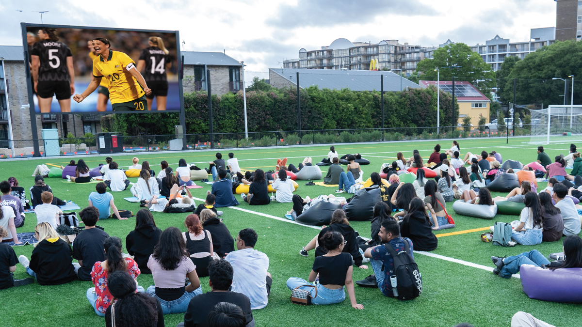 Crowd of people watching sport on an outdoor screen