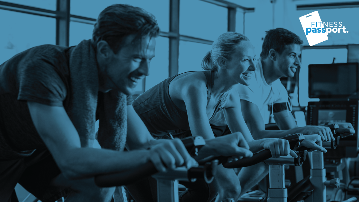 Three people on exercise bikes in black and blue with Fitness Passport logo in top right