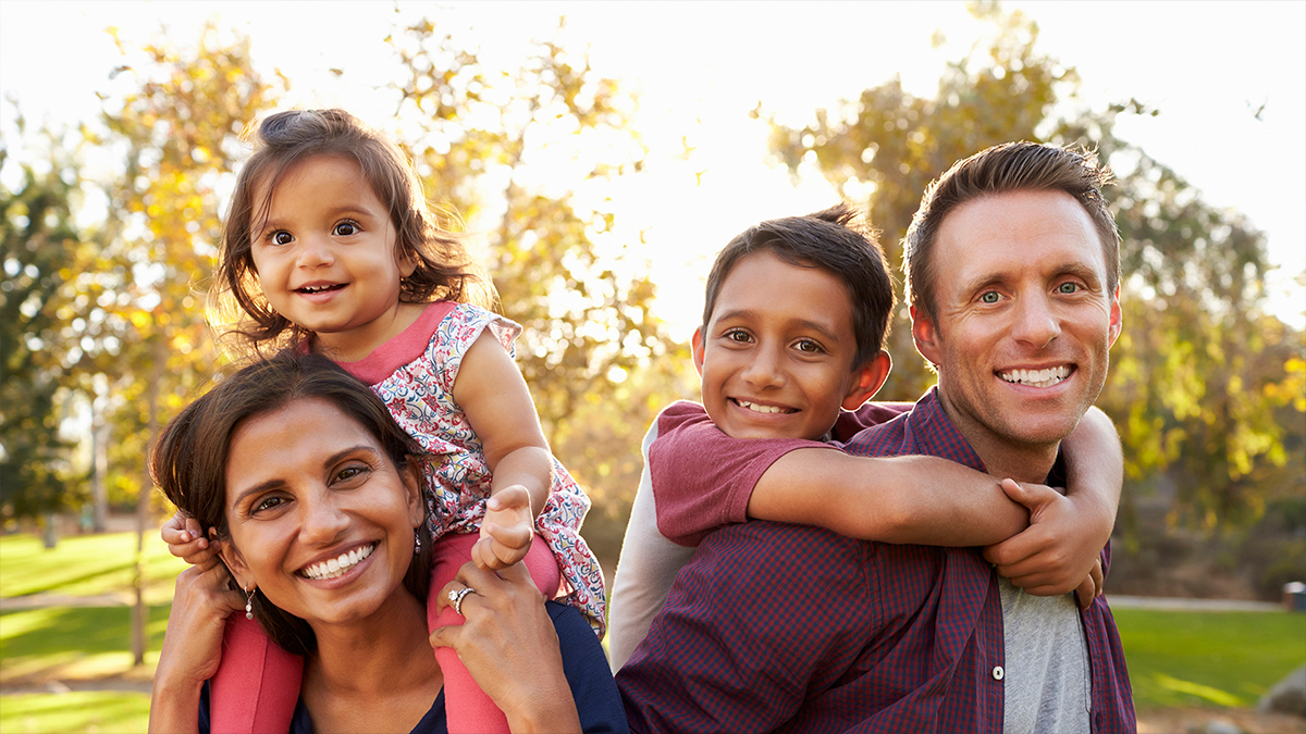 A family of four, outdoors in a park