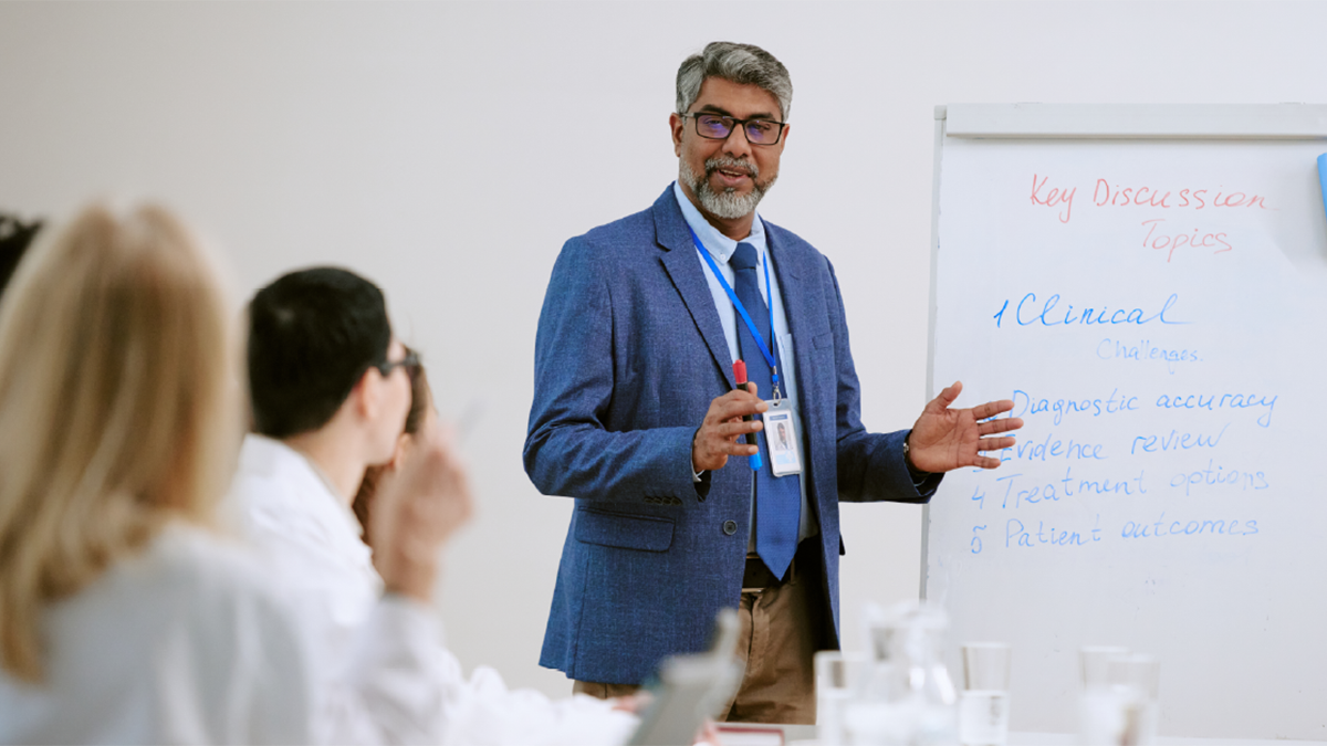 A man standing at a white board in front of a group of people