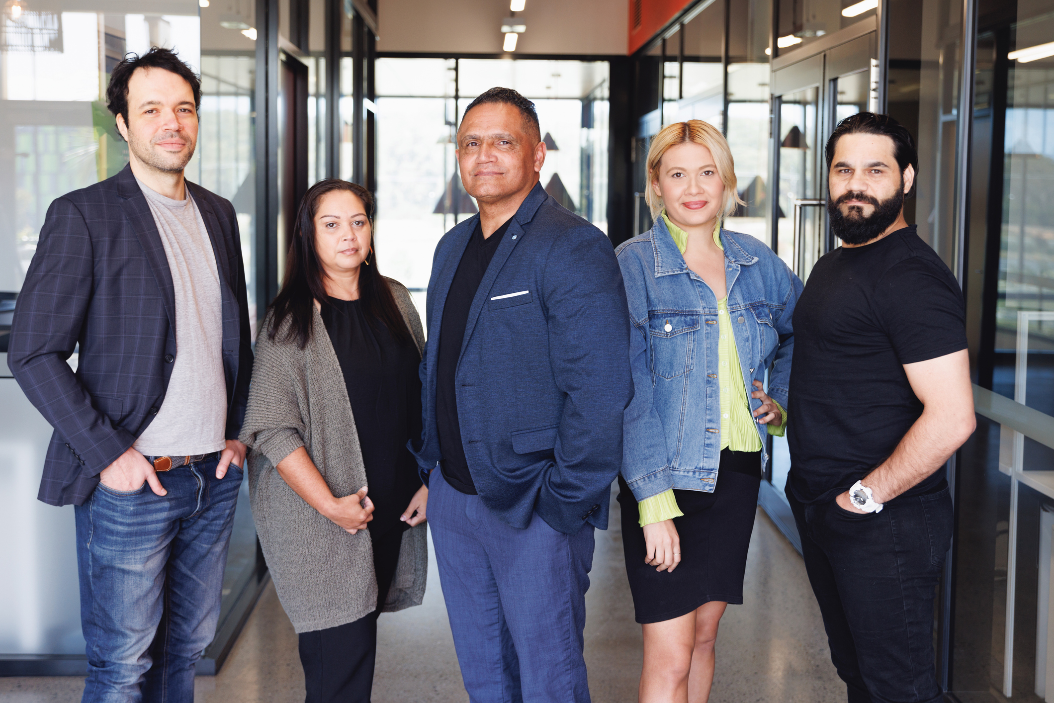 Five Aboriginal Australians stand in front of a modern office building