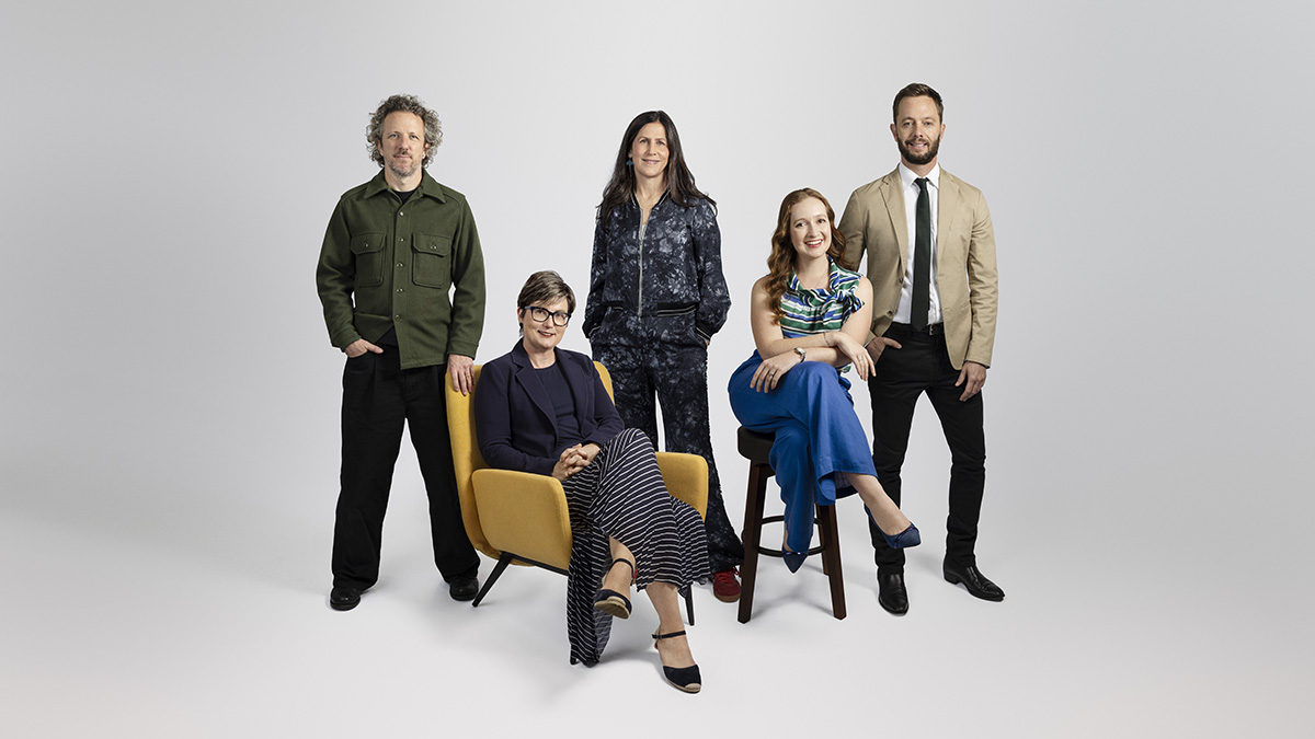 A group of people posed against a grey background