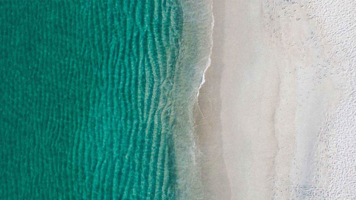 Aerial view of a beach with water on one side and sand on the other