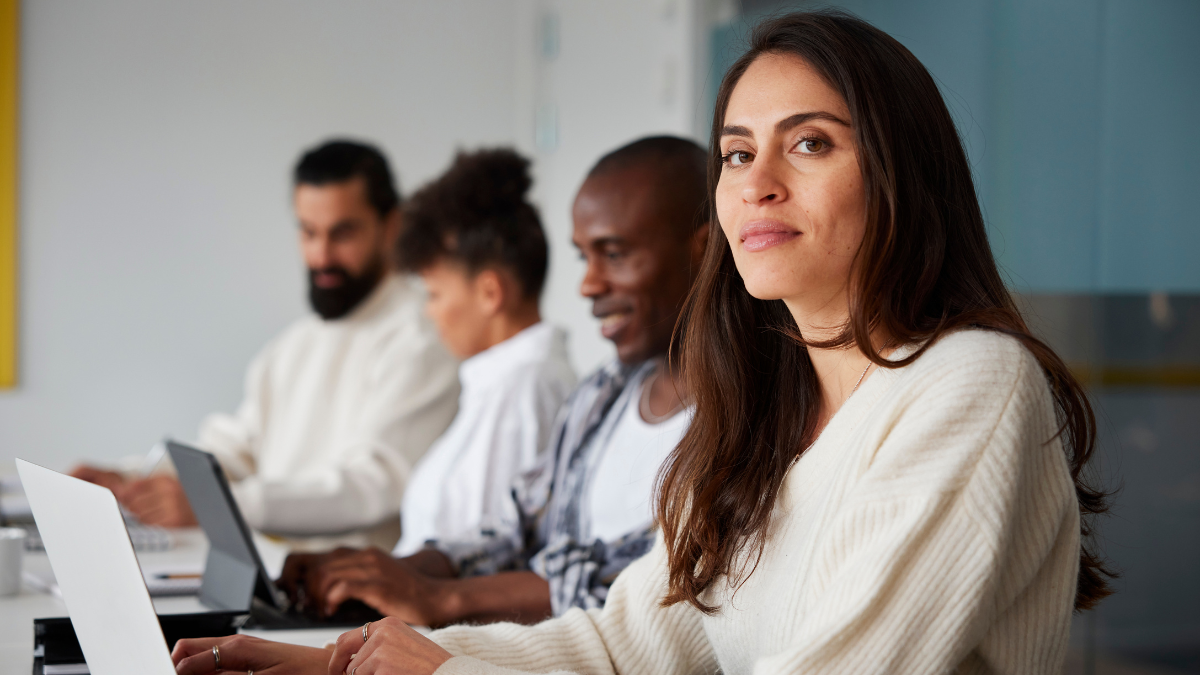 A woman sits at a laptop beside her coworkers