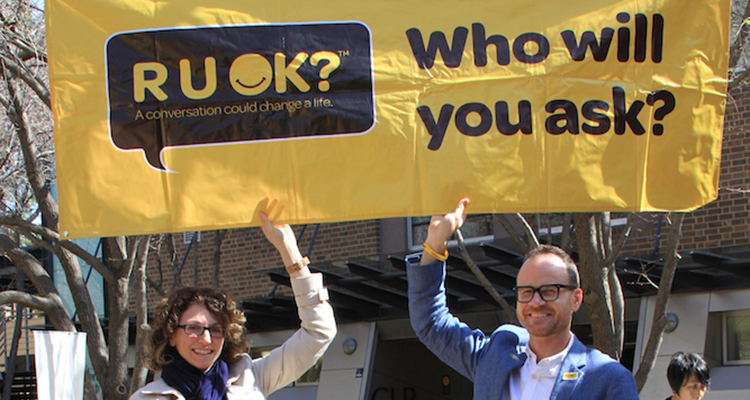 Two people holding up an R U Ok? banner