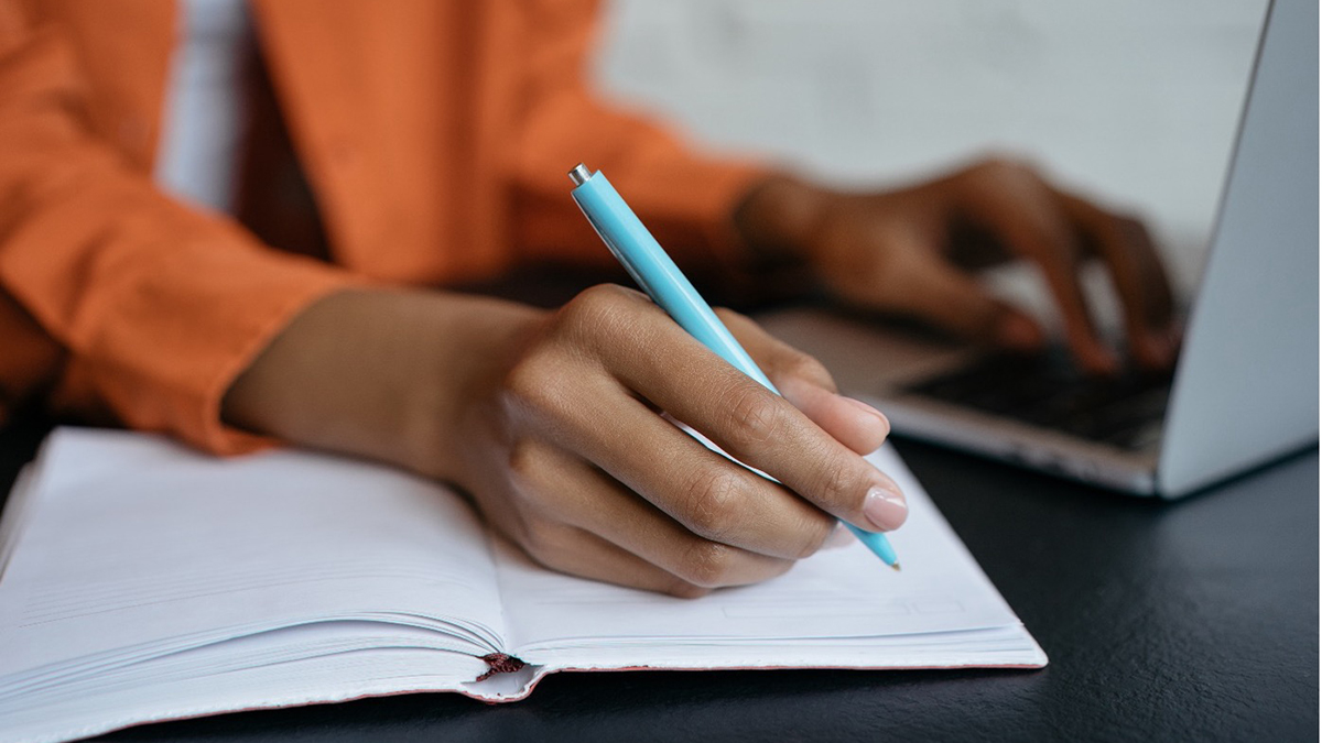 Close-up of a woman's hand holding a pen and writing