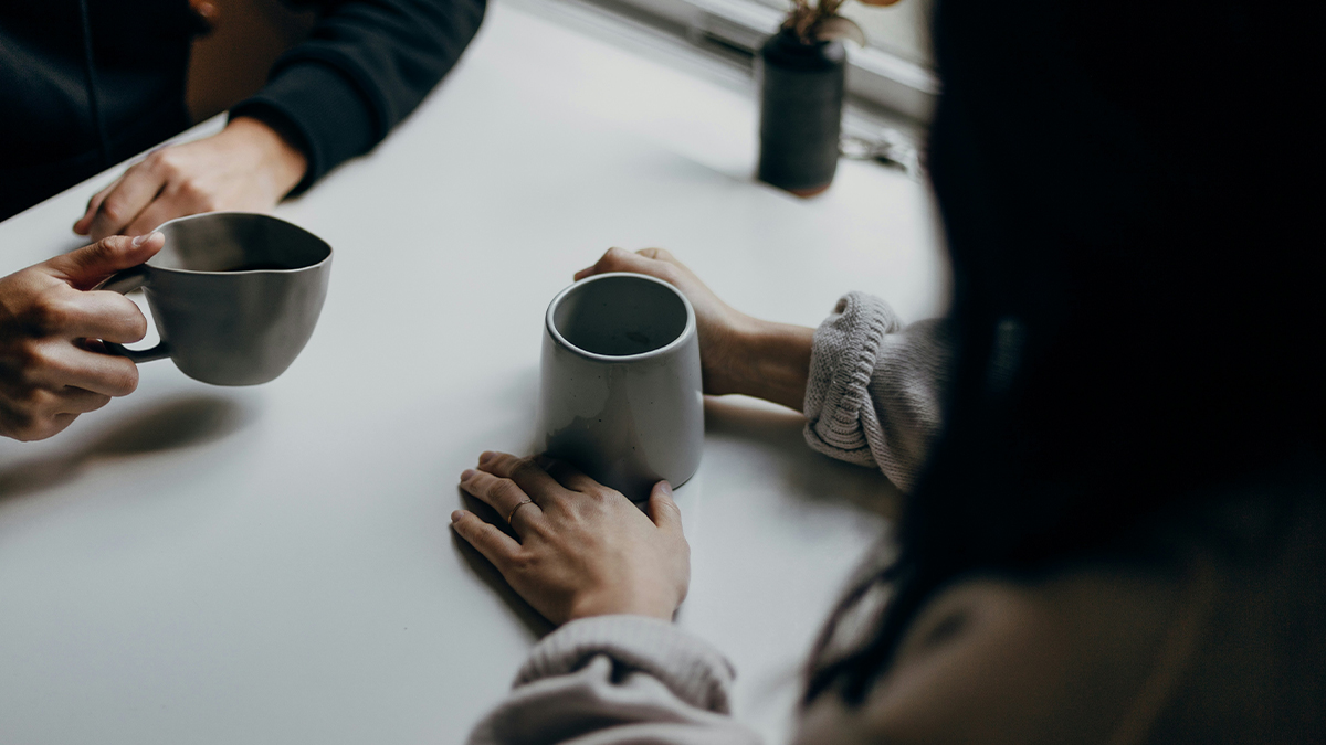 Two people sitting at a table with coffees