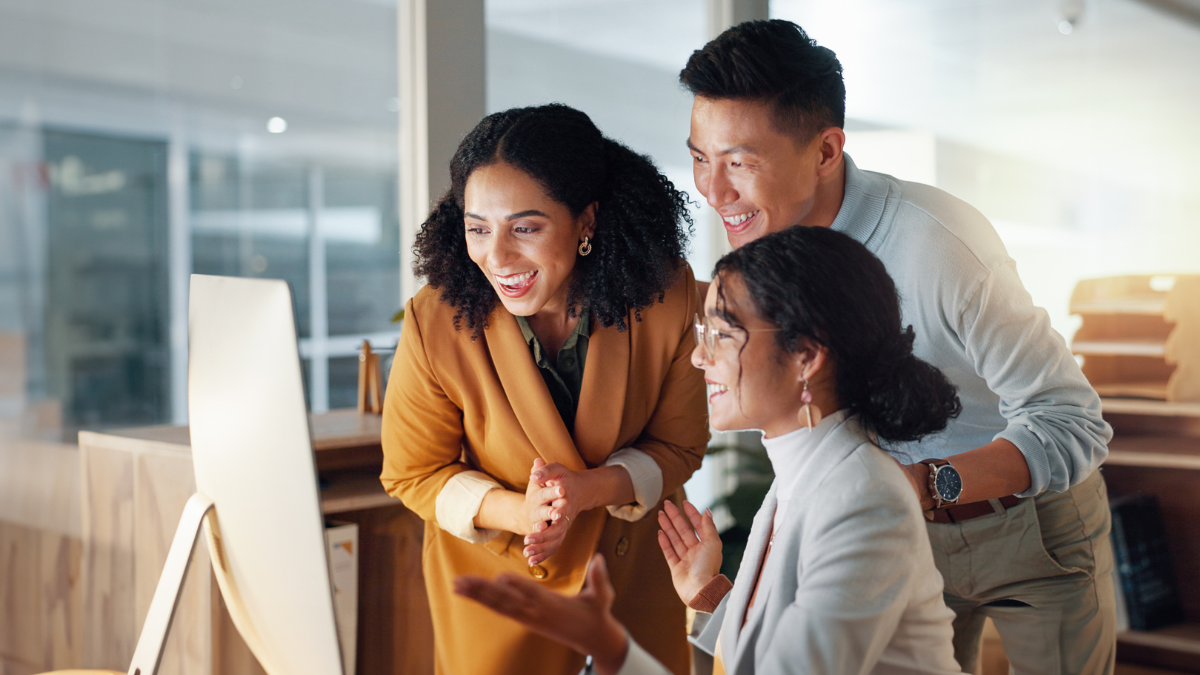 Three people smiling at a computer.