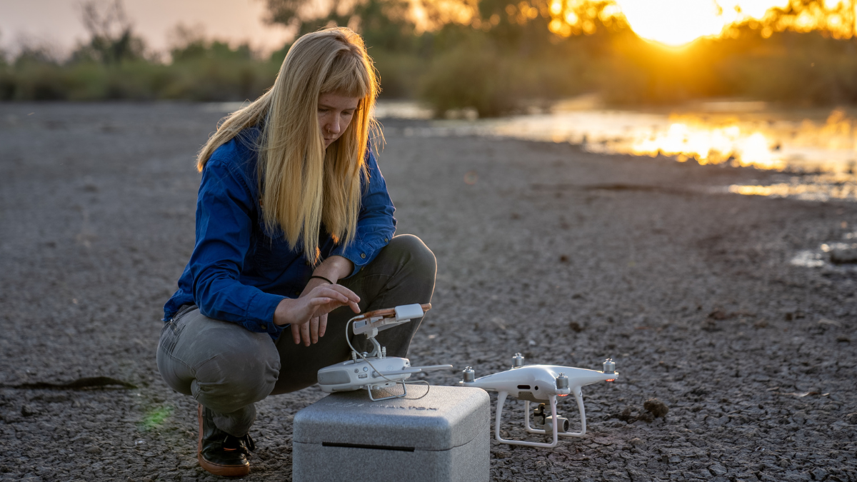 Roxane Francis in the field setting up a drone at sunrise.