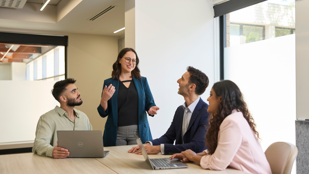 Four professionals discussing happily around a table in an office.