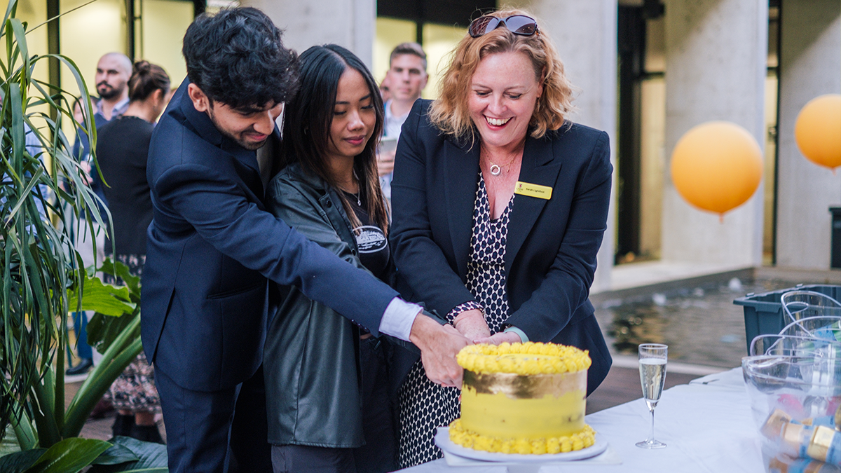 CEO Sarah Lightfoot cutting cake with students 