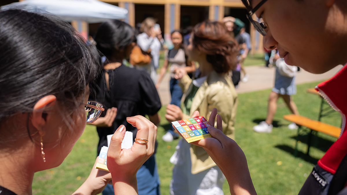 Two people holding cards with SDGs represented