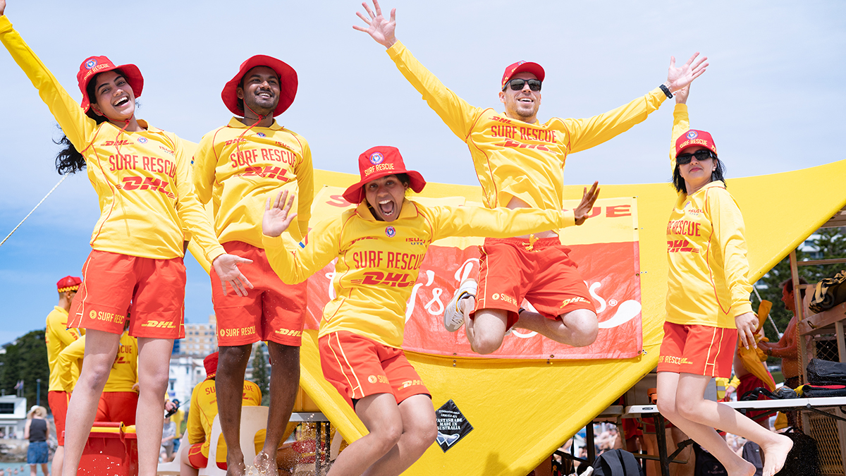 A group of five people dressed in surf rescue outfits jumping in the air