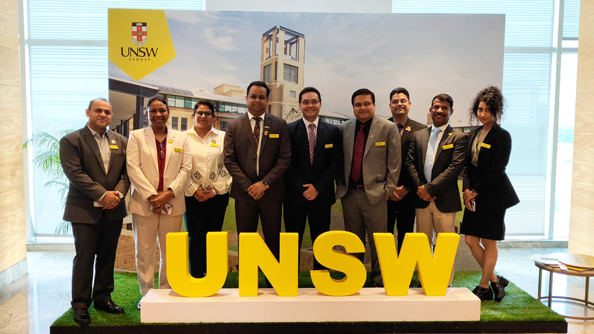 Members of the UNSW team in India, standing behind a yellow UNSW sign