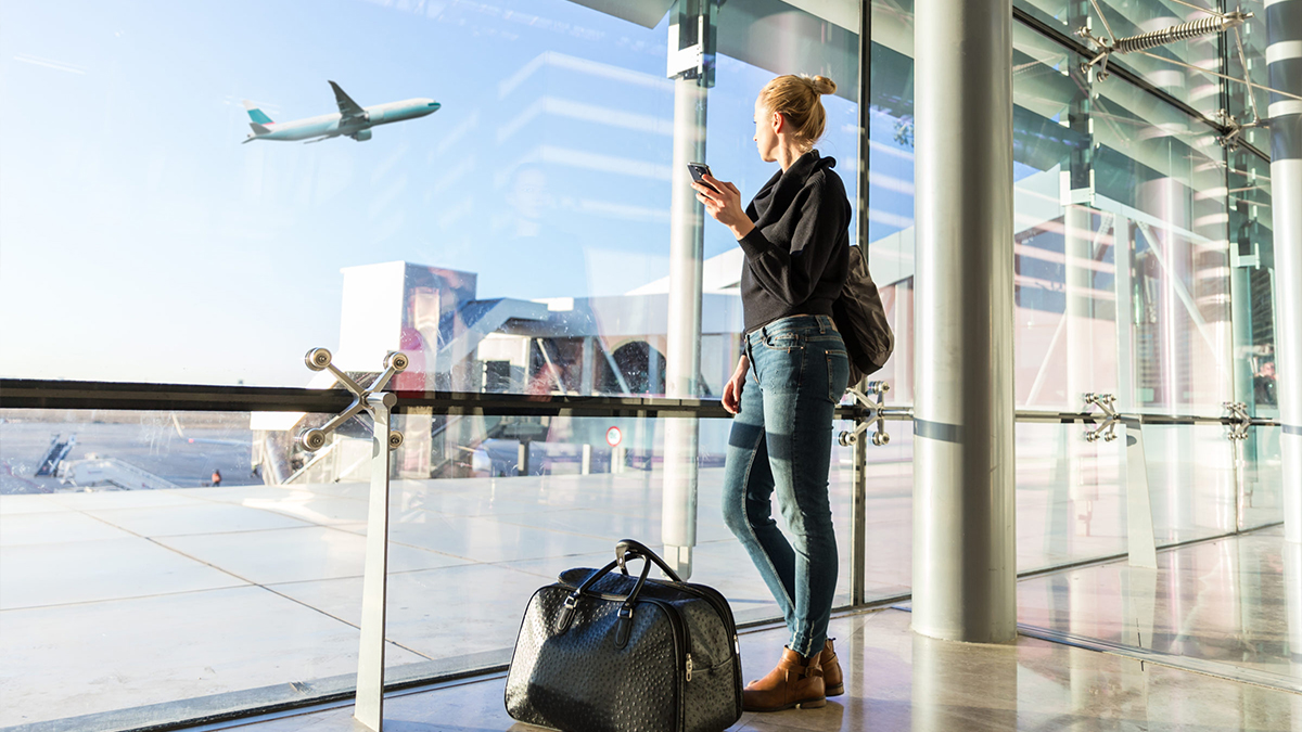 A woman watching an airplane take off from inside the airport