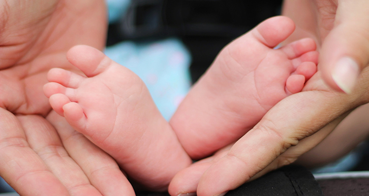 A parent holding their baby's feet