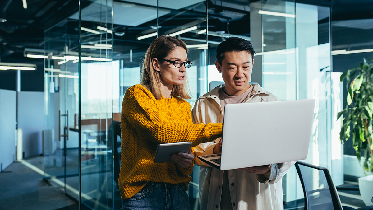 Two people standing and pointing to a laptop screen