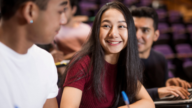 Three students in class smiling