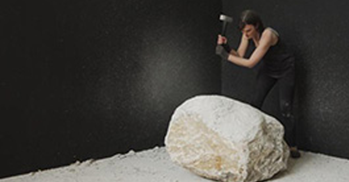 A woman hitting a stone block with a mallet