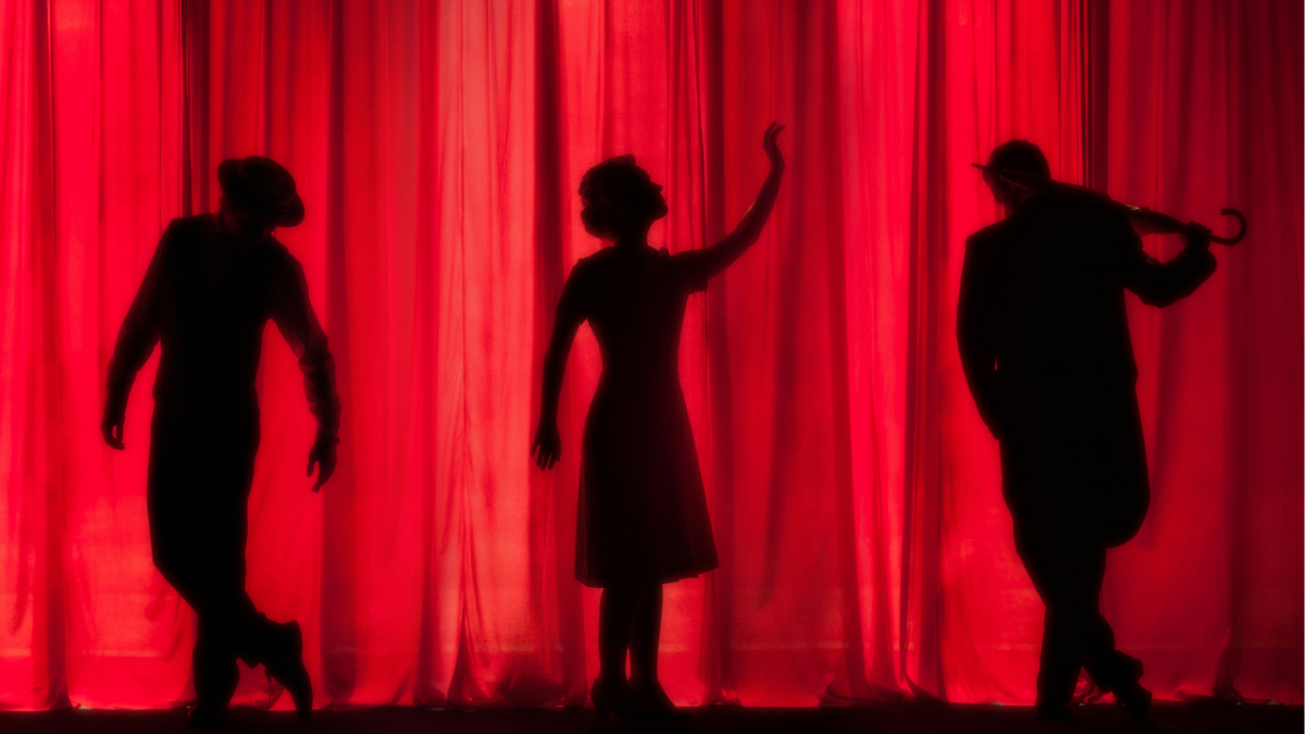 Three silhouettes of musicians against a red curtain backdrop.