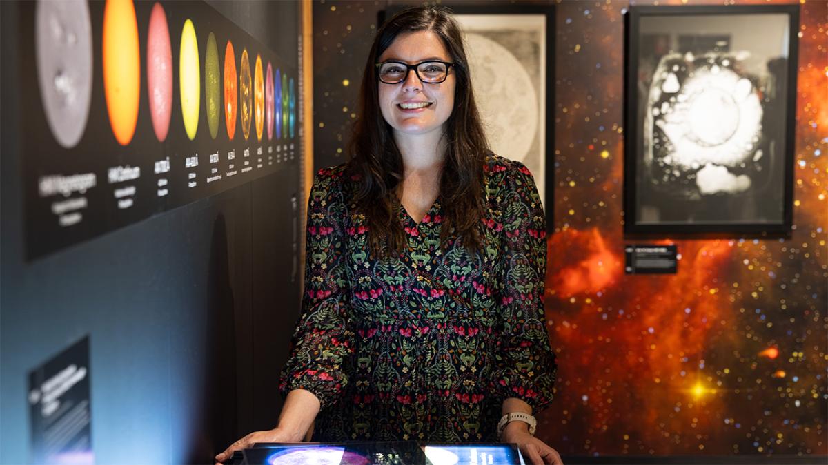 A woman smiling and standing near astrophysics displays
