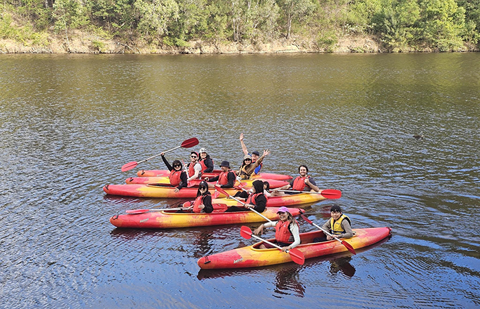 A group of people in two-person kayaks on a river