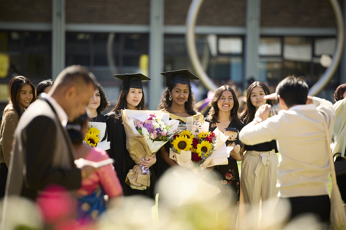 UNSW students stand with flowers waiting to be photographed