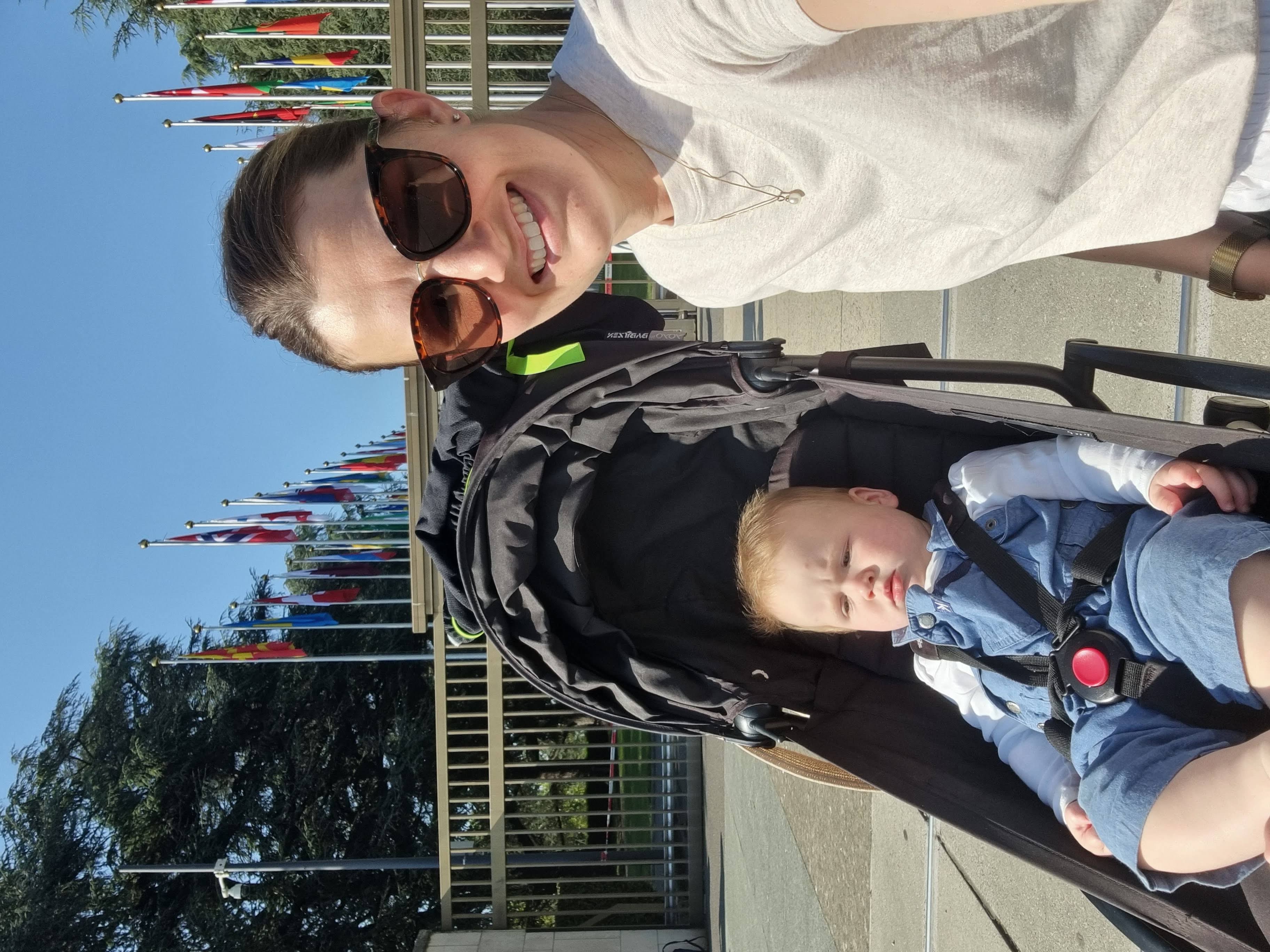 Woman and child sitting in pram on a bridge before rows of flags