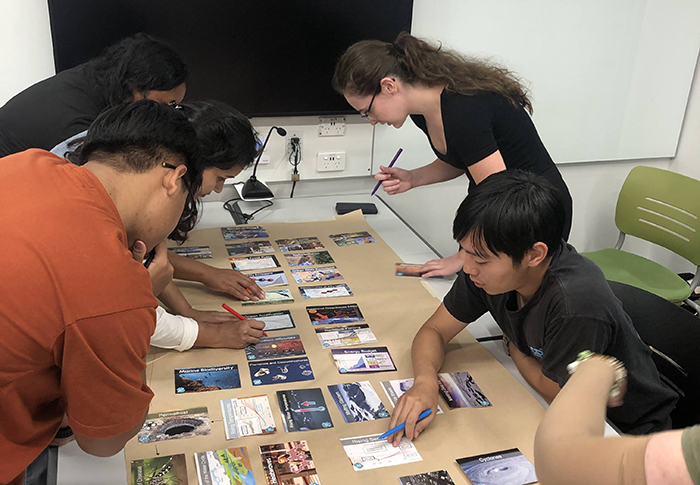 Students at a table with the Climate Fresk card set.