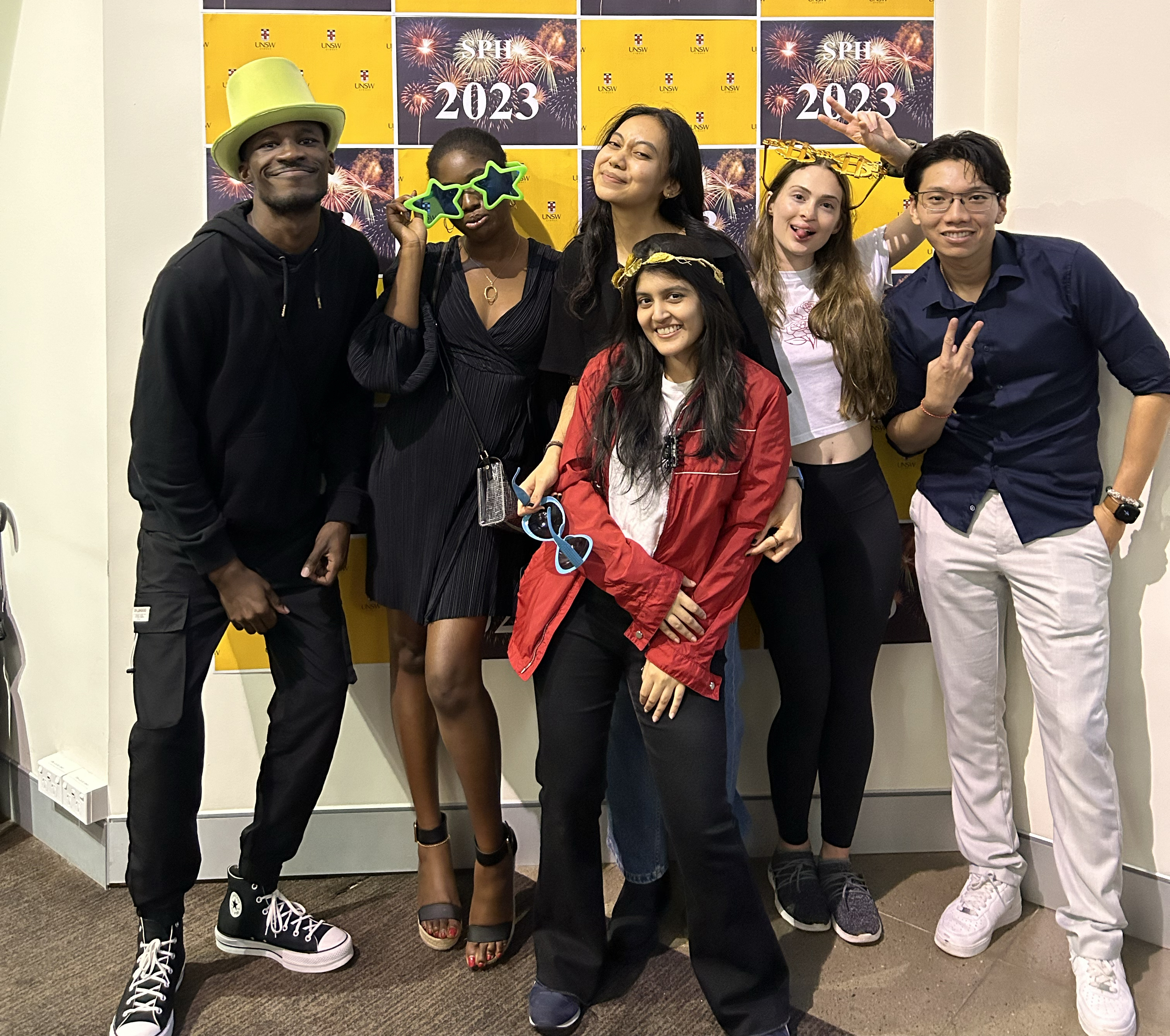 A group of young people posing in front of a sign on New Years Eve