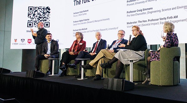 A panel of six people and a sign language interpreter on stage