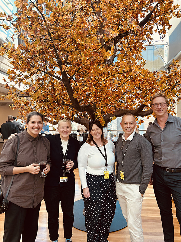 Five UNSW staff members standing in front of a golden-leafed tree