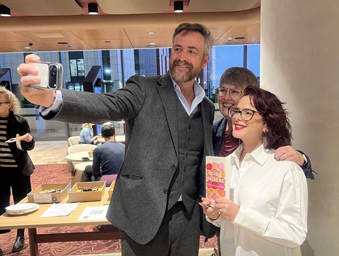 Professor Attila Brungs with two people holding a copy of Being Patient