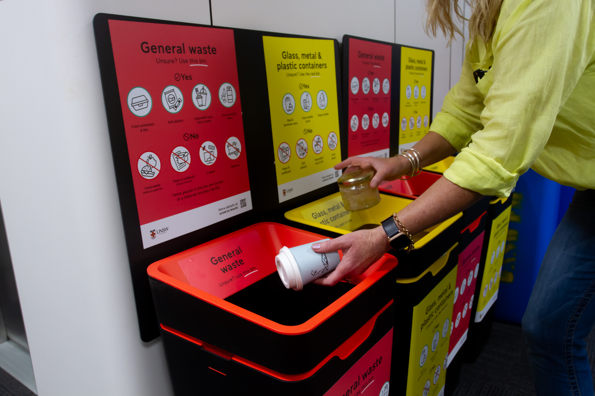 Close up of a woman putting a cup and glass container in bins