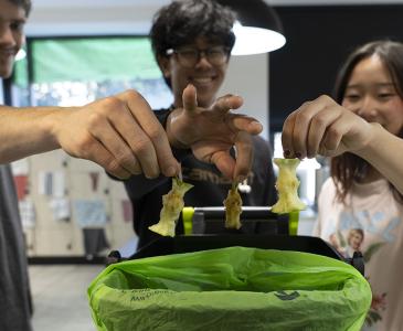 Close up of people holding apple cores over food waste bins