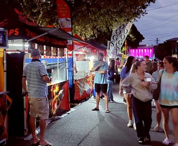 People walking through a night market with food stalls